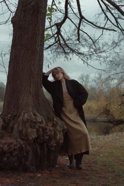 editorial portrait of model leaning by tree in Amsterdam